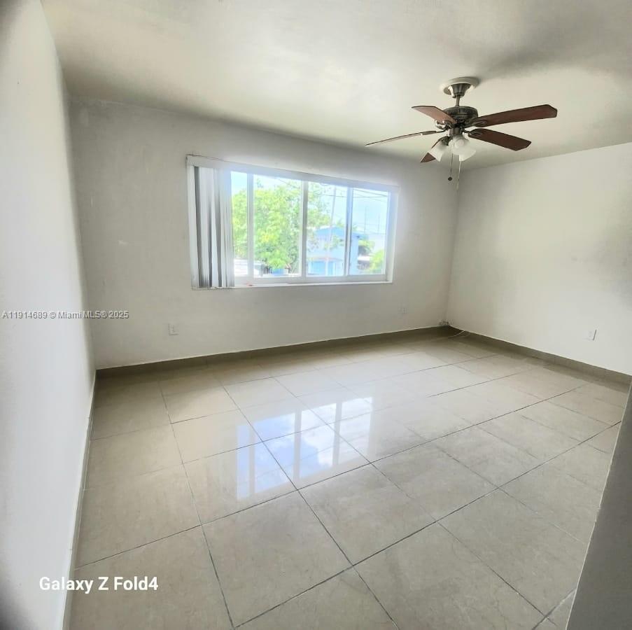 An empty room features white walls, light-colored tile flooring, and a ceiling fan — 2400 NW 10th Ave # 4, Miami FL 33127, MIAMI, FL