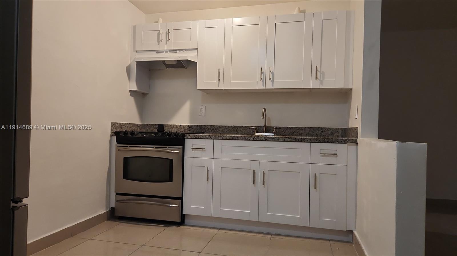 A kitchen features white shaker cabinets, stainless steel appliances, and a granite countertop — 2400 NW 10th Ave # 4, Miami FL 33127, MIAMI, FL