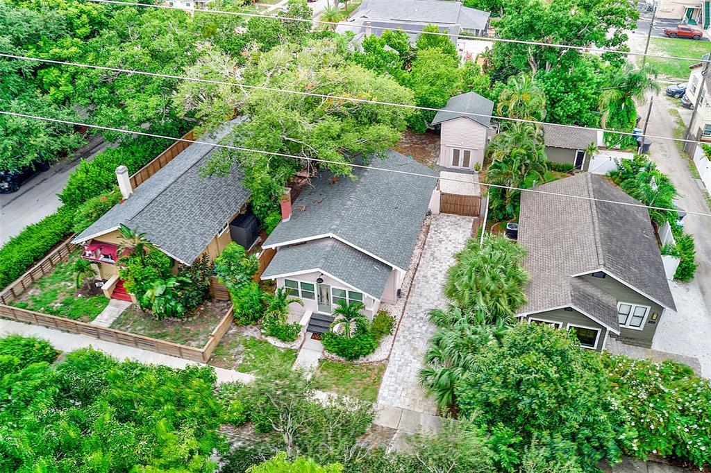 An aerial view shows three houses with gray roofs, a paved driveway, and lush landscaping — 440 22ND STREET N, ST PETERSBURG, FL