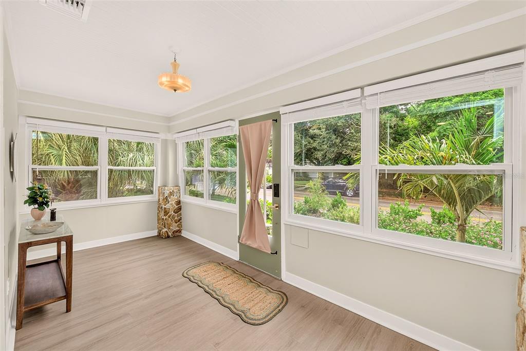 A sunroom with light wood-look flooring, large windows, and a green door with a curtain — 440 22ND STREET N, ST PETERSBURG, FL