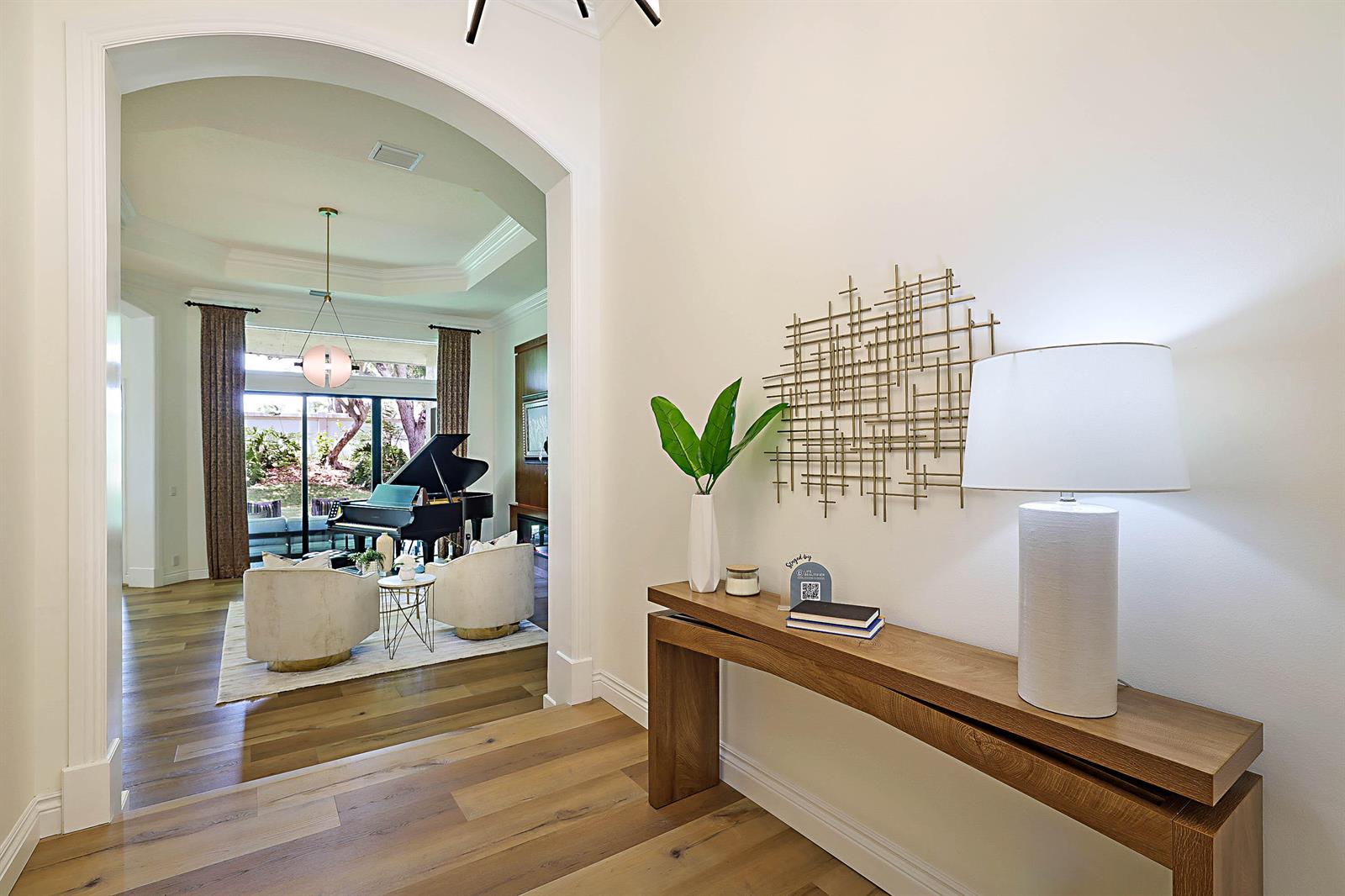 A living room features a grand piano, two armchairs, and a wood-paneled accent wall — 7153 Via Abruzzi, Lake Worth FL 33467, LAKE WORTH, FL