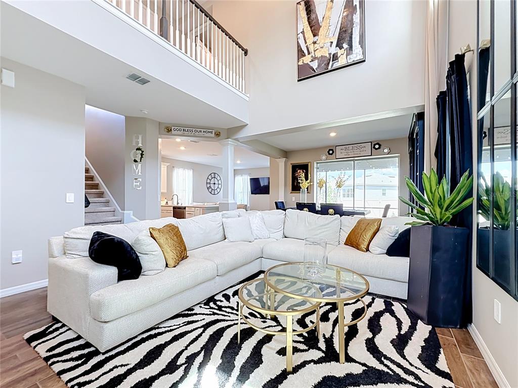 A living room features a white sectional sofa, zebra-print rug, and glass coffee tables — 2854 HIGH POINTE STREET, CLERMONT, FL