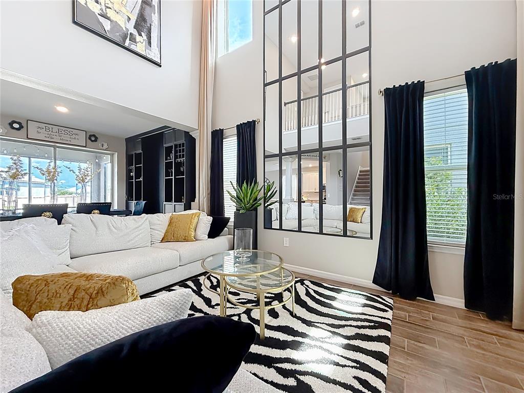 A living room features a double-height ceiling, a large grid mirror, and a zebra-print rug — 2854 HIGH POINTE STREET, CLERMONT, FL