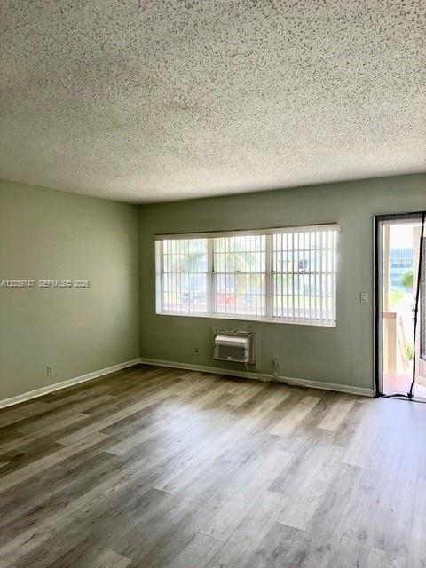 An empty room with light wood-look flooring, a window with blinds, and a wall-mounted air conditioner — 119 Salisbury, West Palm Beach FL 33417, WEST PALM BEACH, FL