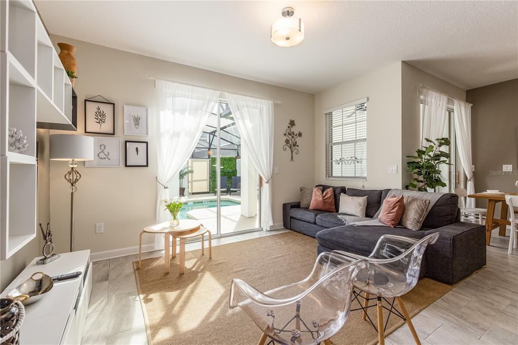 A living room features a grey sectional sofa, two clear chairs, and a sliding door — 4802 LOVE STOREY LANE, KISSIMMEE, FL