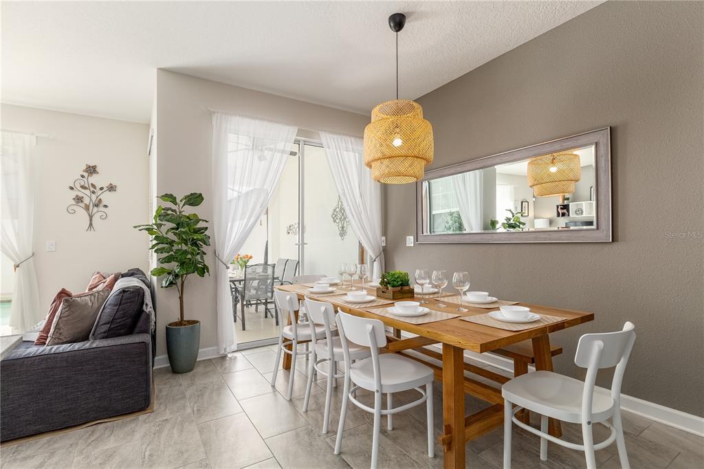 A dining area features a wooden table, white chairs, a woven pendant light, and a mirror — 4802 LOVE STOREY LANE, KISSIMMEE, FL