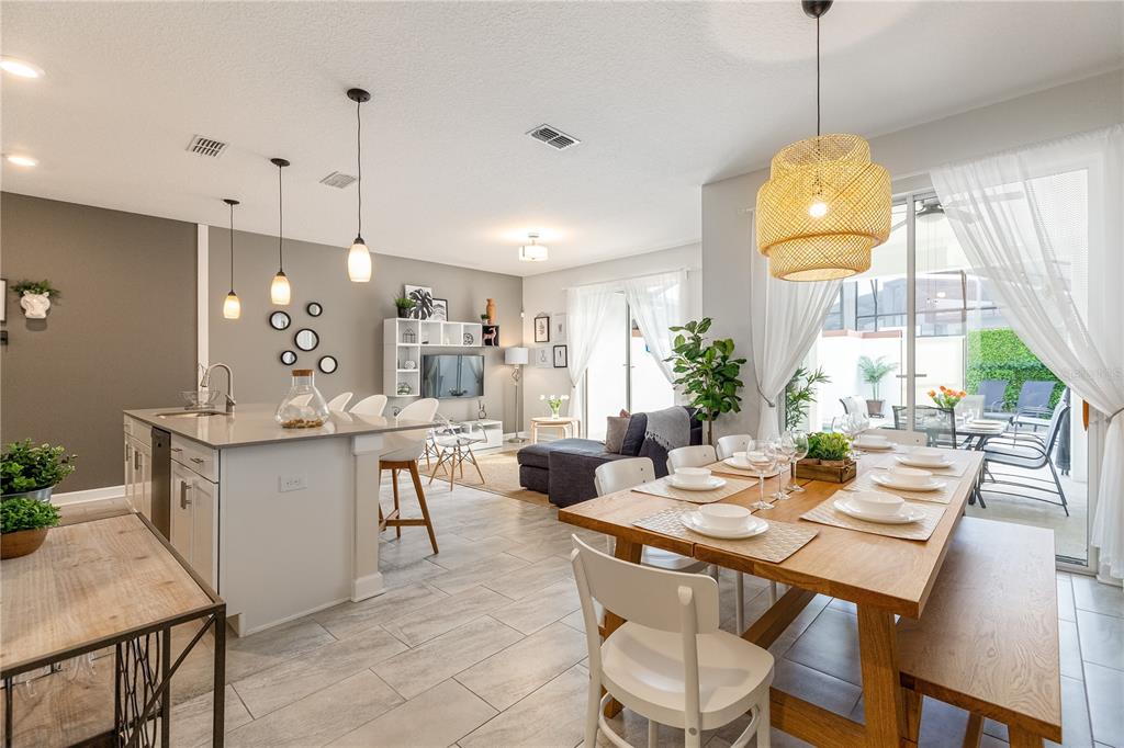 An open-concept kitchen, dining area, and living room featuring tile floors and neutral walls — 4802 LOVE STOREY LANE, KISSIMMEE, FL