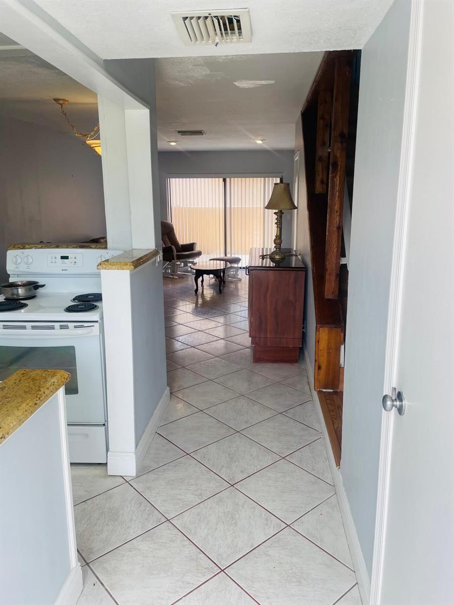 A view from a kitchen toward a living area with tile floors and a staircase — 139 Sparrow Drive # 2c, Royal Palm Beach FL 33411, ROYAL PALM BEACH, FL