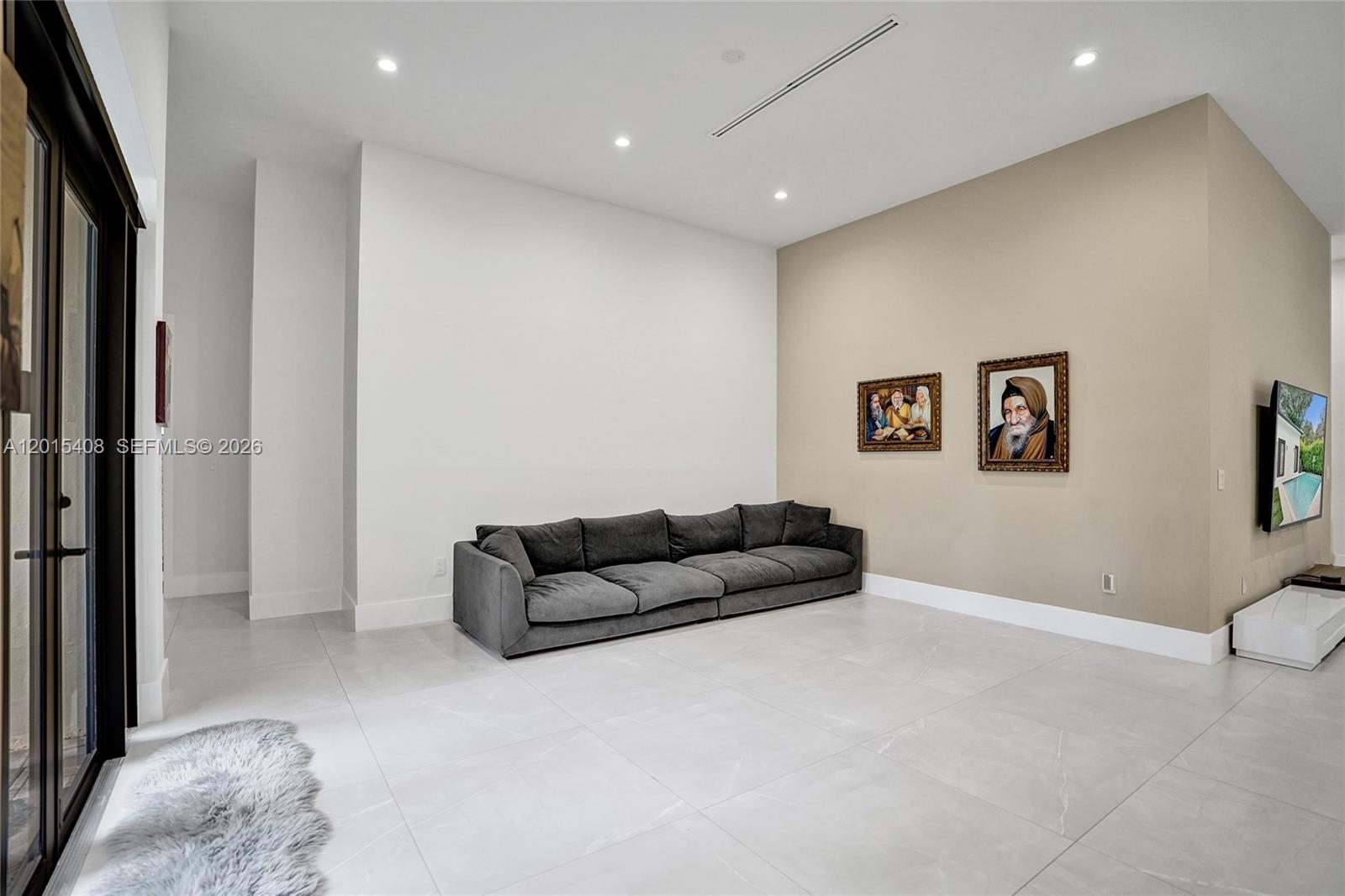 A modern living room features a grey sofa, tiled floors, and two framed portraits — 3909 SW 54th Ct, Dania Beach FL 33312, DANIA BEACH, FL