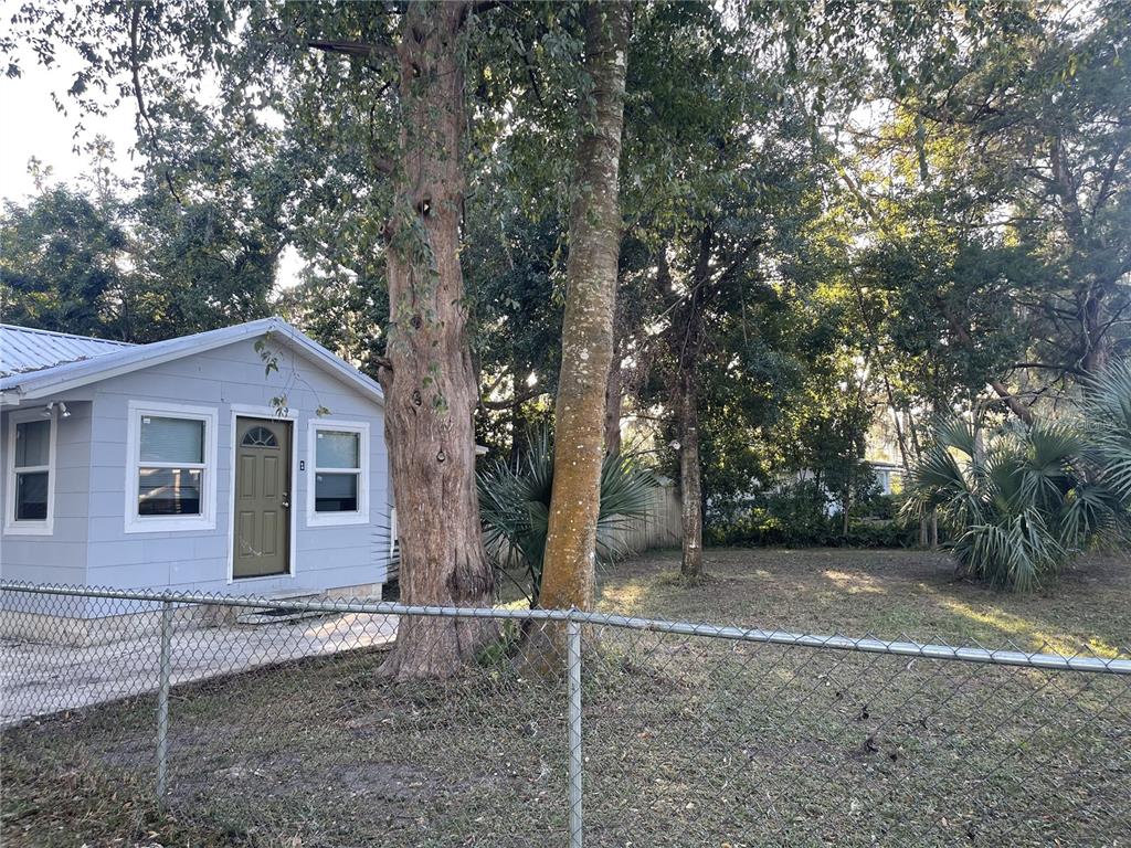 An aerial view shows a light blue house with a metal roof surrounded by dense trees — 6220 SE 118TH PLACE, BELLEVIEW, FL