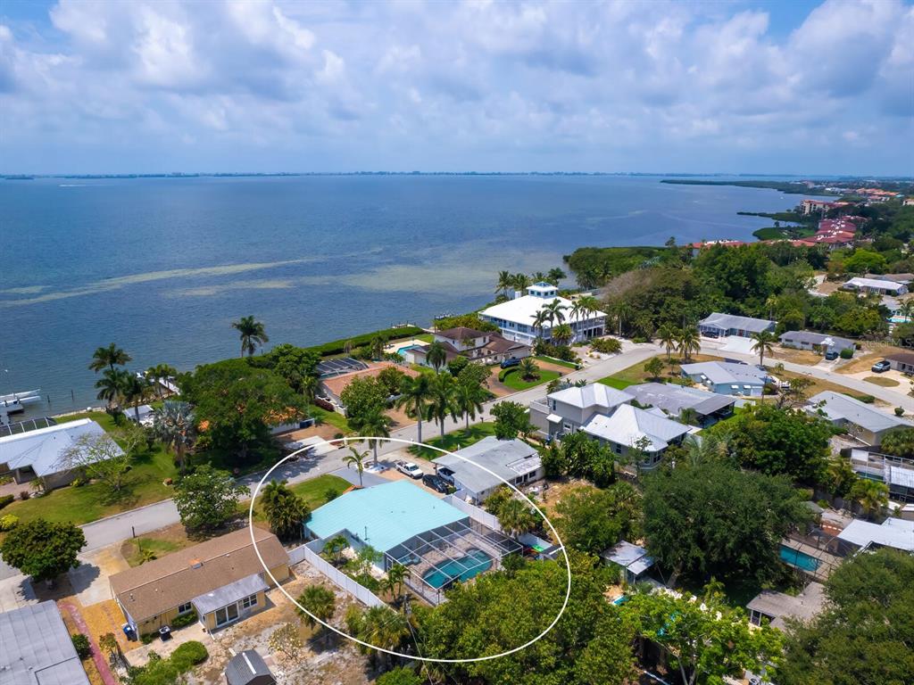 An aerial view shows a single-story house with a screened-in pool near the water — 3115 BAY DRIVE, BRADENTON, FL