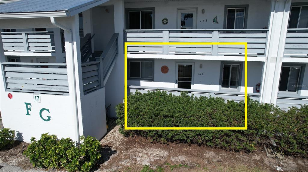 A ground-floor apartment exterior features a small patio enclosed by a wooden railing and bushes — 6800 PLACIDA ROAD UNIT 163, ENGLEWOOD, FL