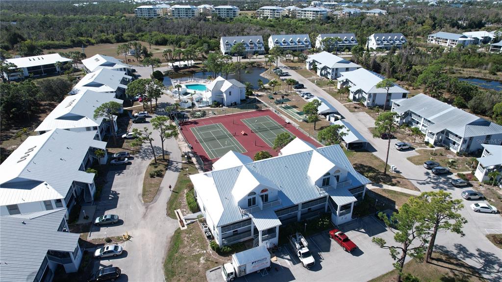 An aerial view shows a multi-building residential complex with tennis courts and a swimming pool — 6800 PLACIDA ROAD UNIT 163, ENGLEWOOD, FL