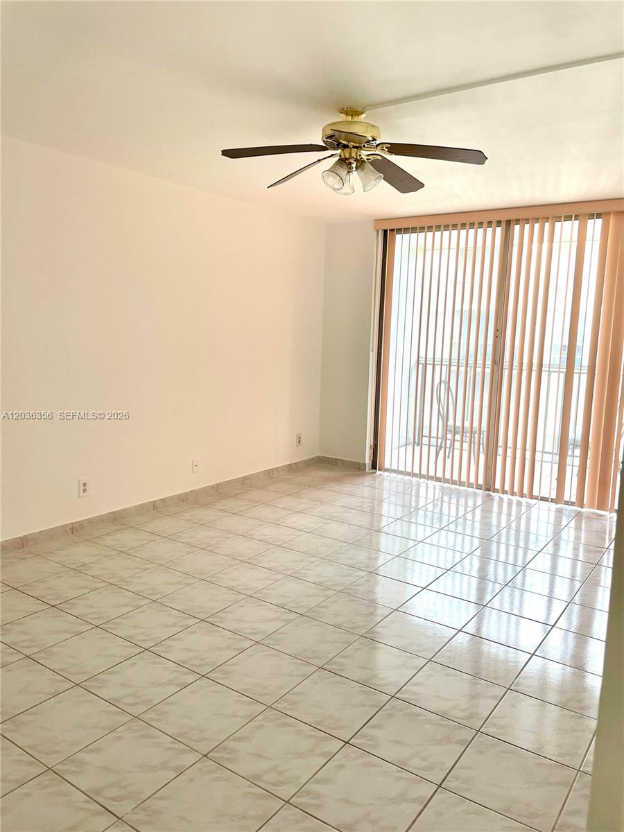 An empty room features light-colored tile flooring, a ceiling fan, and sliding glass balcony doors — 851 Three Islands Blv # 414, Hallandale Beach FL 33009, HALLANDALE BEACH, FL
