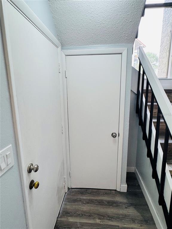 A hallway features two white doors, wood-look flooring, and a staircase with a black railing — 4100 PLAYER CIRCLE UNIT 101, ORLANDO, FL