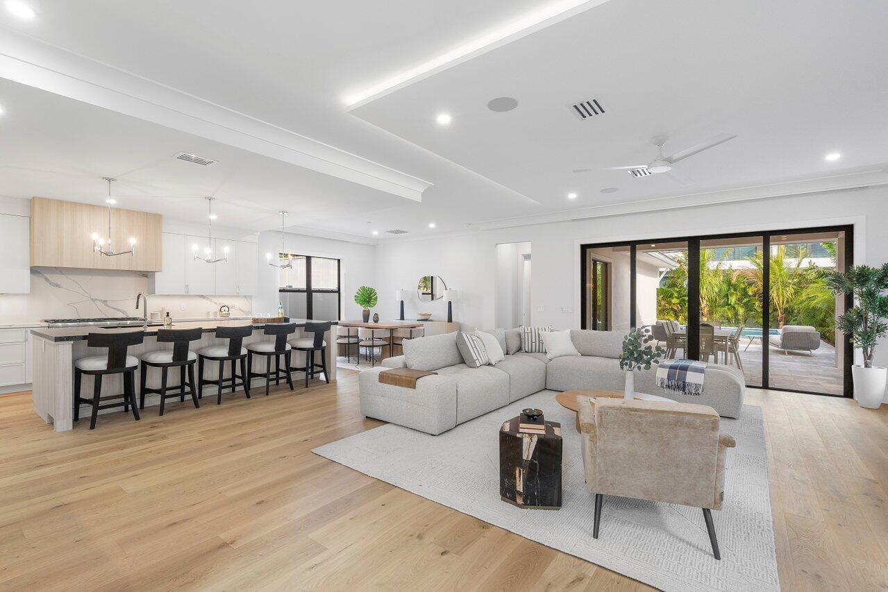 A modern living room features a large gray sectional, wooden stairs, and sliding glass doors — 725 SE 4th Avenue, Delray Beach FL 33483, DELRAY BEACH, FL