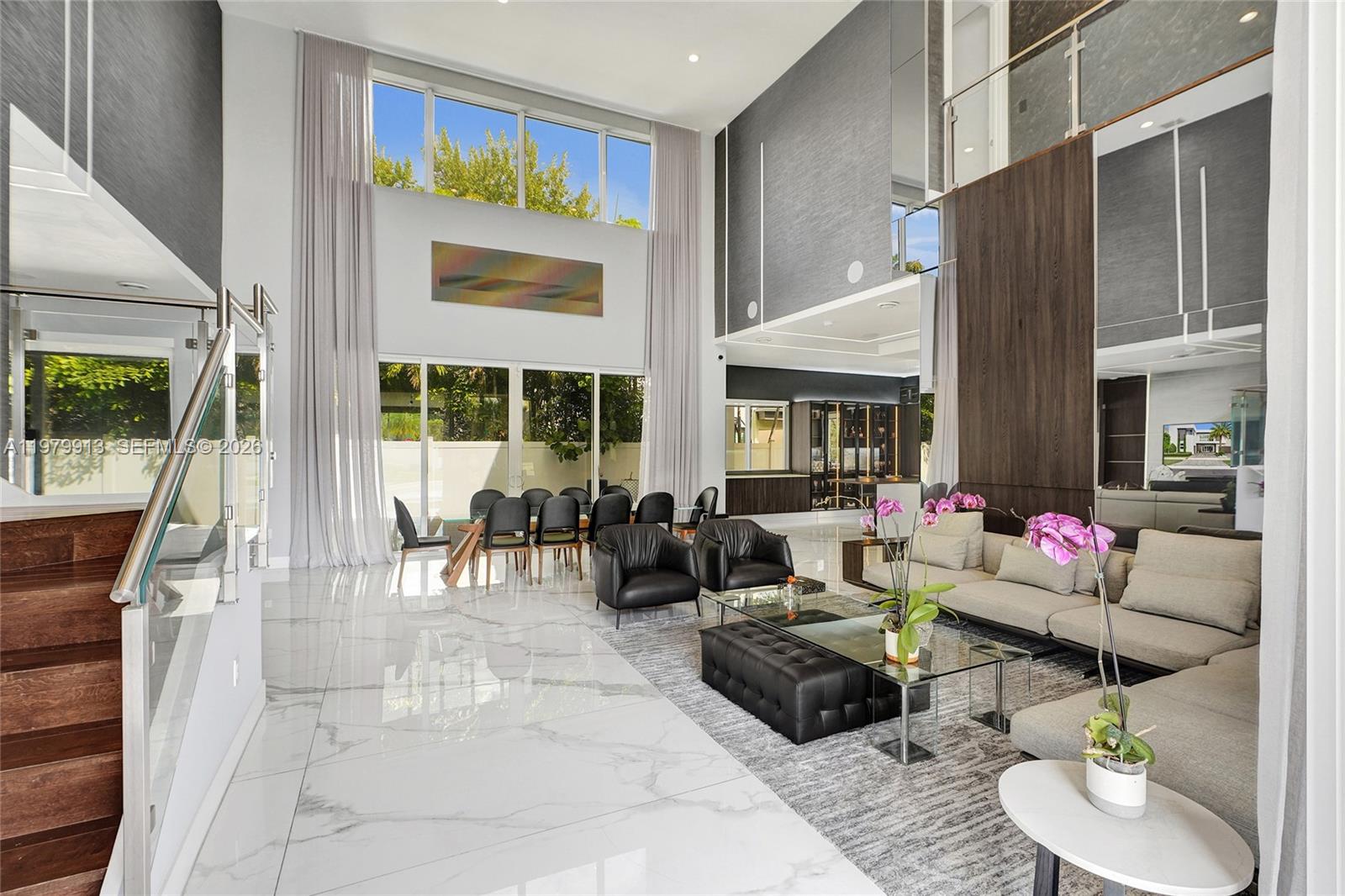 A spacious living and dining area features double-height ceilings, marble floors, and floor-to-ceiling windows — 10223 NW 75th Ter, Doral FL 33178, DORAL, FL