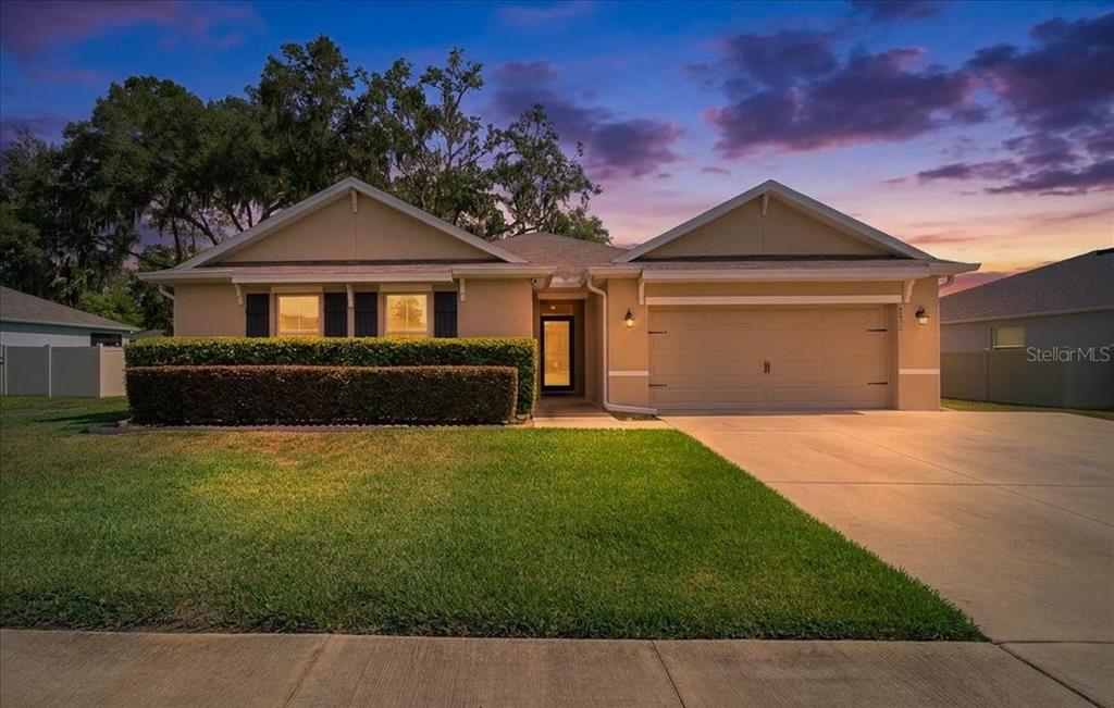 A single-story house with a beige exterior, a two-car garage, and a manicured front lawn — 5025 NE 15TH PLACE, OCALA, FL