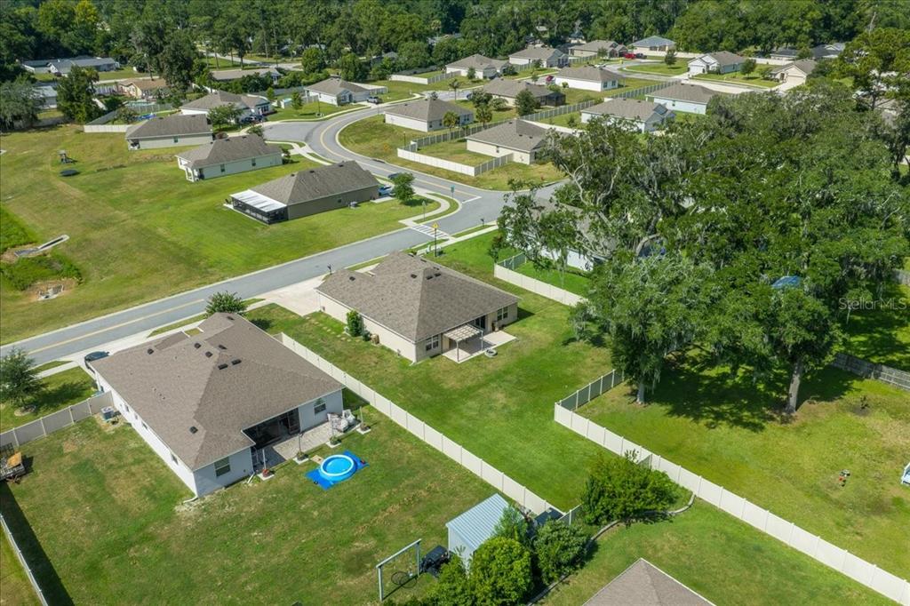 An aerial view shows suburban houses with fenced backyards and a winding residential street — 5025 NE 15TH PLACE, OCALA, FL
