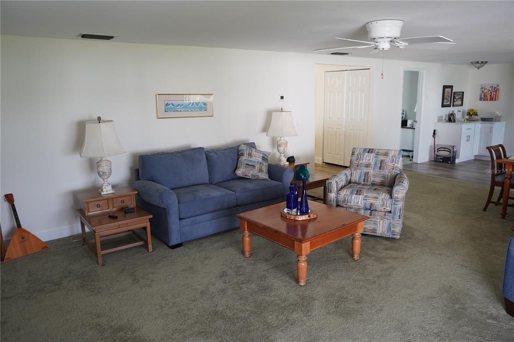 A living room features a blue sofa, patterned armchair, wooden coffee table, and green carpeting — 536 FLAMINGO DRIVE, APOLLO BEACH, FL