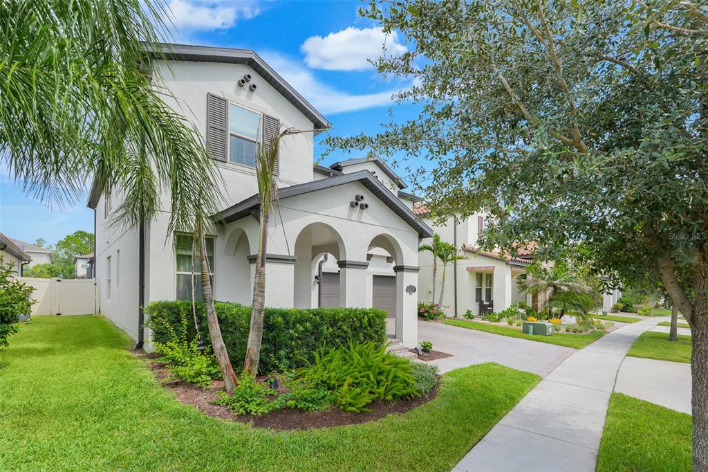 A two-story stucco house with a covered entryway, arched columns, and a paved driveway — 8254 PROCIDA ISLE LANE, WINDERMERE, FL