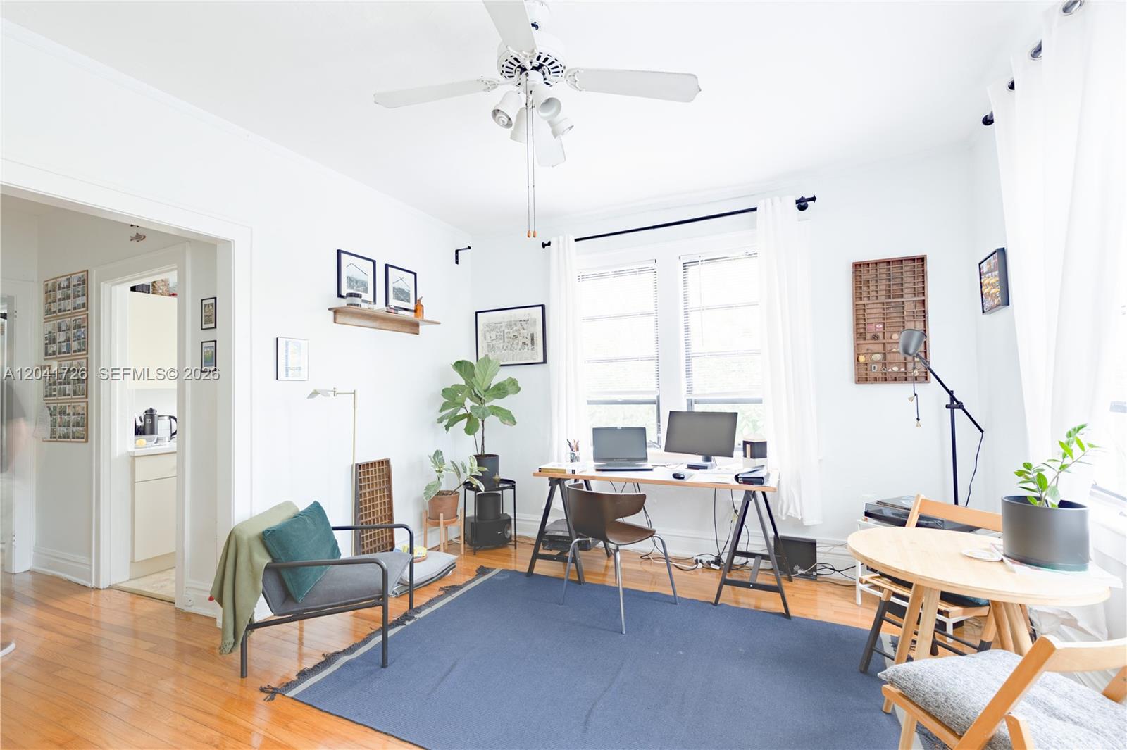 A home office features a desk, a seating area, a blue rug, and hardwood floors — 320 Mendoza Ave # 3, Miami FL 33134, MIAMI, FL