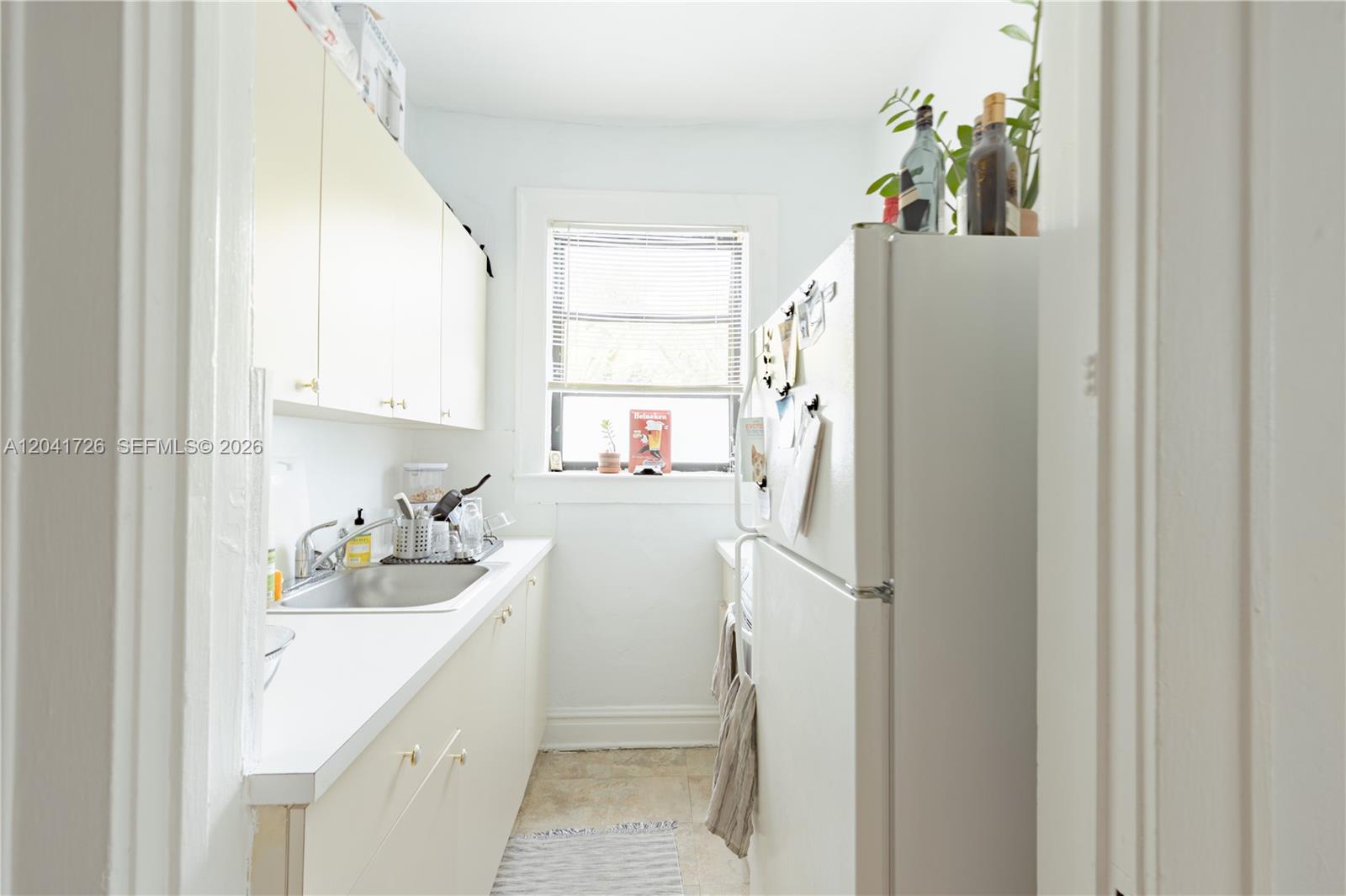 A narrow kitchen features white cabinets, a stainless steel sink, and a white refrigerator — 320 Mendoza Ave # 3, Miami FL 33134, MIAMI, FL