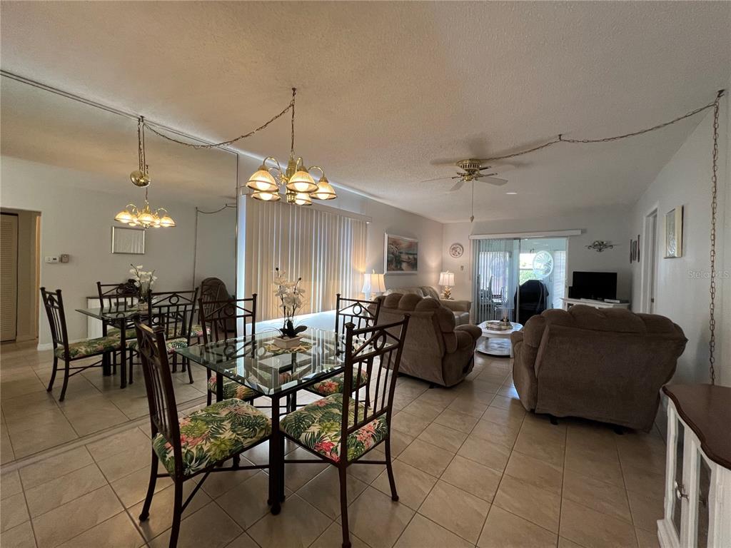 A dining area with a glass table and chairs sits adjacent to a living room — 3668 TROPHY BOULEVARD, NEW PORT RICHEY, FL