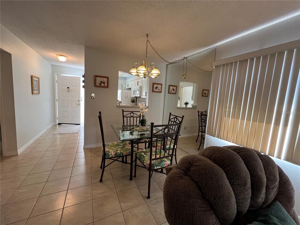 A dining area with a glass table and chairs sits adjacent to a tiled entryway — 3668 TROPHY BOULEVARD, NEW PORT RICHEY, FL