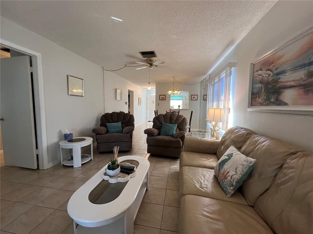 A living room features tile flooring, a leather sofa, two recliners, and a coffee table — 3668 TROPHY BOULEVARD, NEW PORT RICHEY, FL