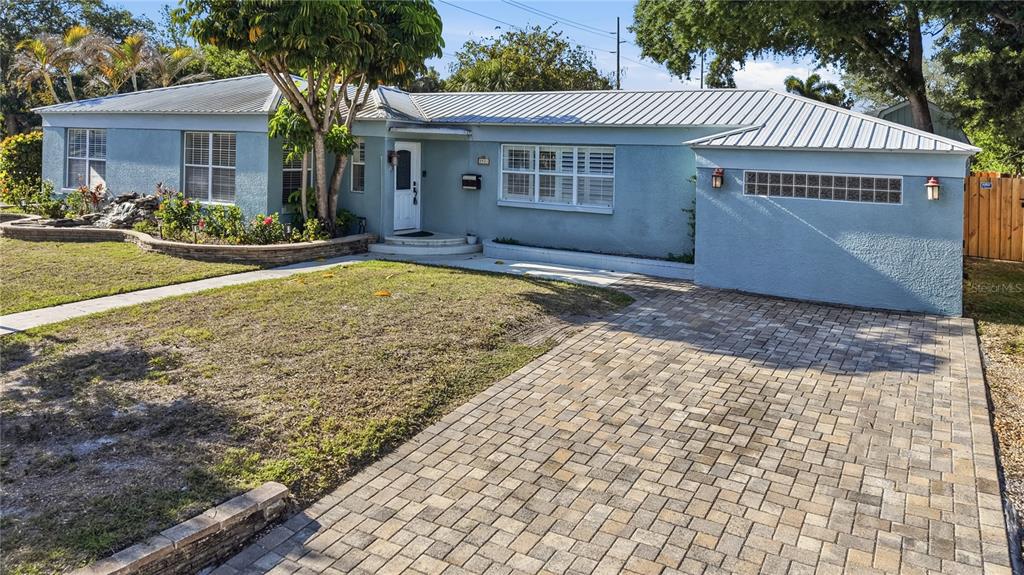 A light blue single-story house features a metal roof, paver driveway, and a front garden — 3921 W BAY TO BAY BOULEVARD, TAMPA, FL
