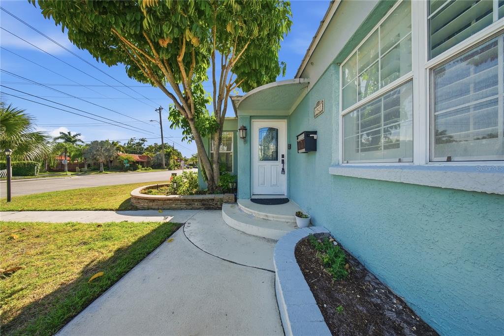 A teal house exterior features a white front door, a curved awning, and landscaping — 3921 W BAY TO BAY BOULEVARD, TAMPA, FL