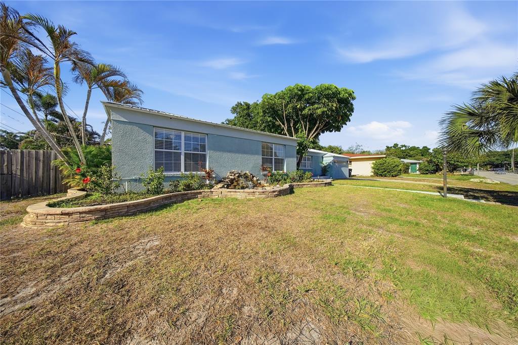 A light blue house with a stone-bordered garden bed and a small fountain in front — 3921 W BAY TO BAY BOULEVARD, TAMPA, FL