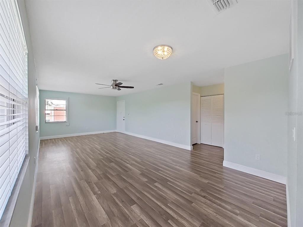 An empty room features light blue walls, wood-look flooring, a ceiling fan, and a closet — 5973 TERRACE PARK DRIVE N UNIT 311, ST PETERSBURG, FL