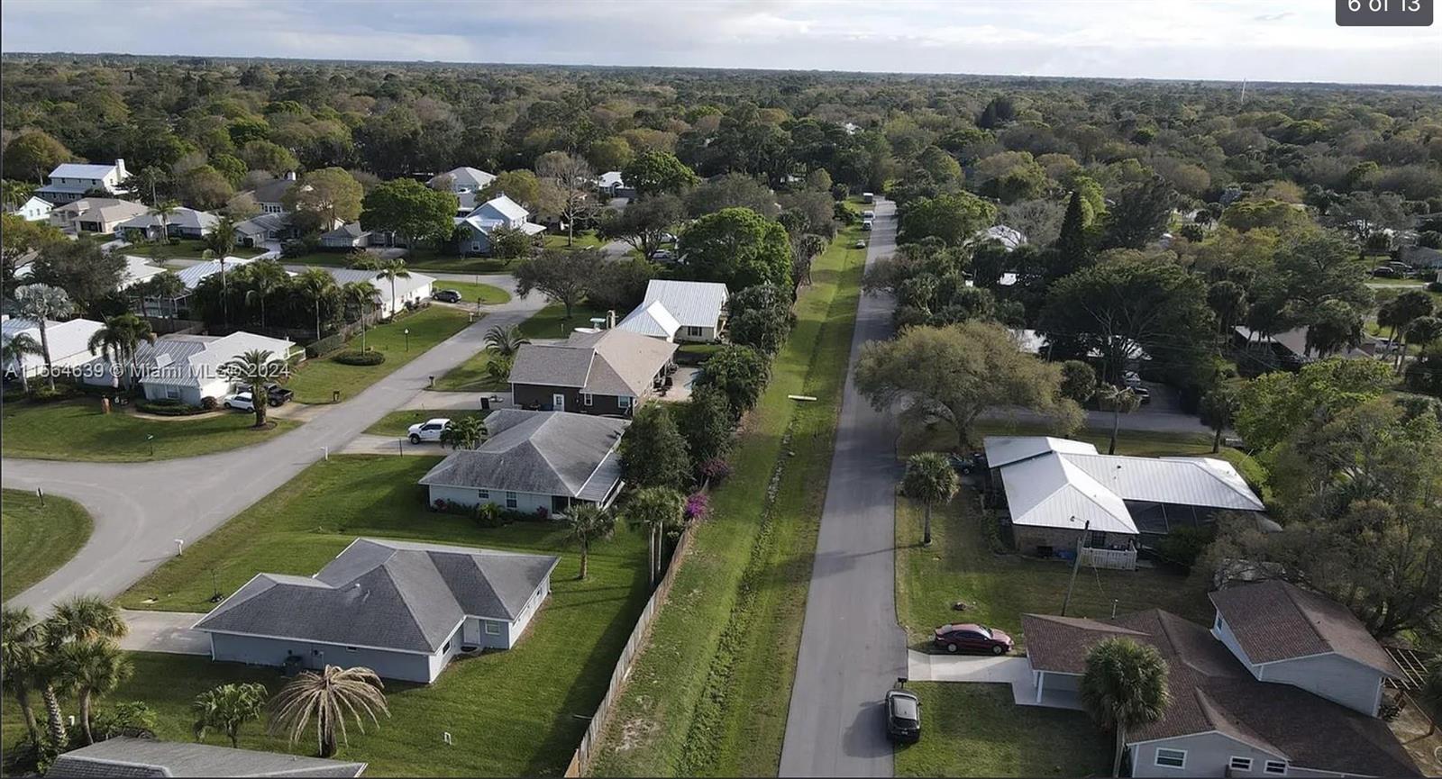 An aerial view shows a suburban neighborhood with houses, green lawns, and a paved road — 755 38th Court, Vero Beach FL 32968, VERO BEACH, FL
