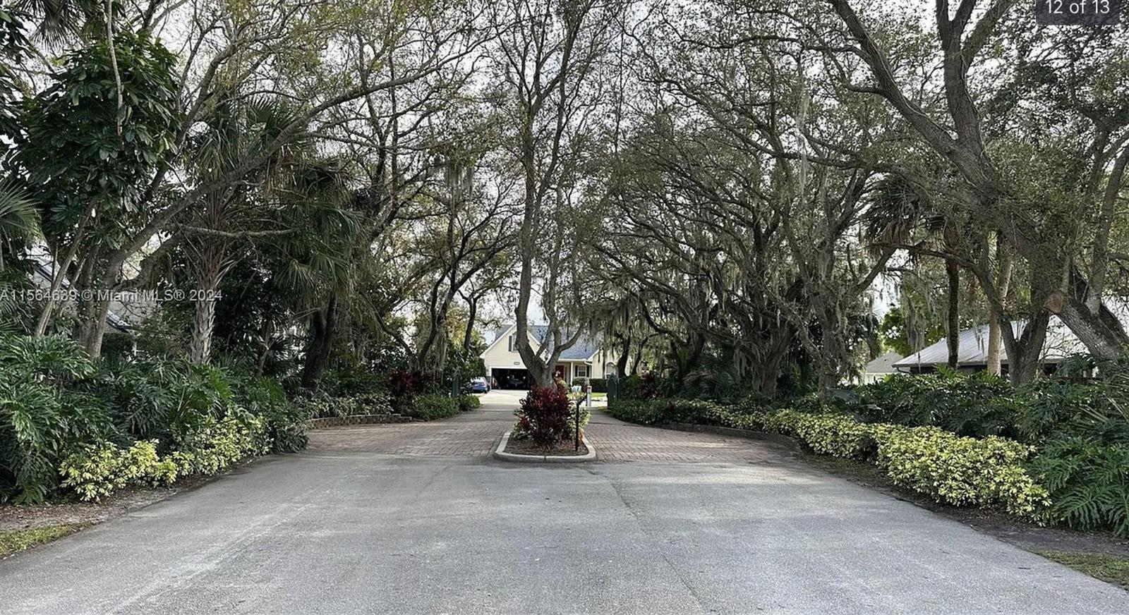 A paved driveway leads toward a house framed by large, moss-draped trees — 755 38th Court, Vero Beach FL 32968, VERO BEACH, FL