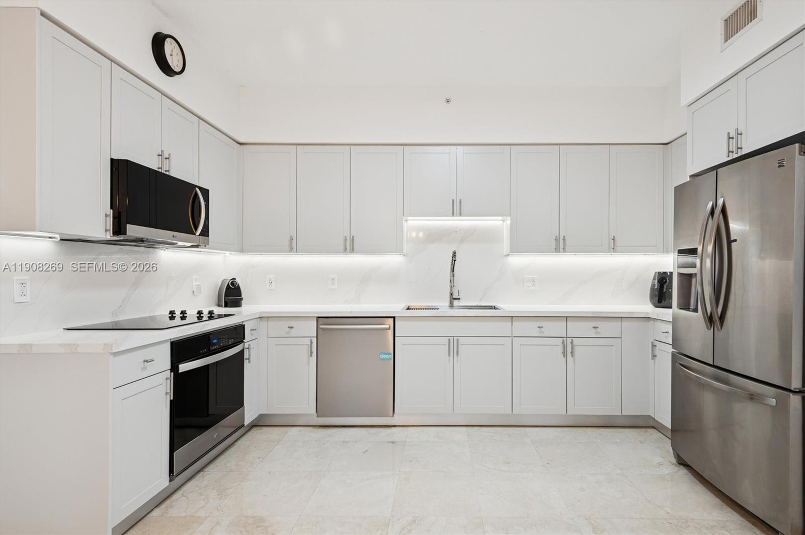 A modern kitchen features white cabinets, stainless steel appliances, and white marble-style countertops and backsplash — 717 Crandon Blvd # 507, Key Biscayne FL 33149, KEY BISCAYNE, FL