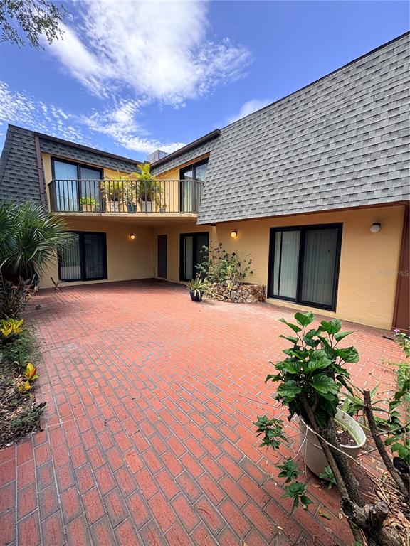 A two-story building with a brick patio, a second-floor balcony, and large sliding glass doors — 18 CEDAR DUNES DRIVE, NEW SMYRNA BEACH, FL