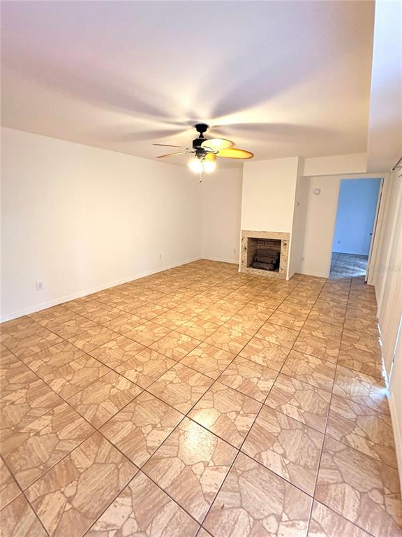 A living room features light-colored tile flooring, a ceiling fan, and a brick fireplace — 18 CEDAR DUNES DRIVE, NEW SMYRNA BEACH, FL