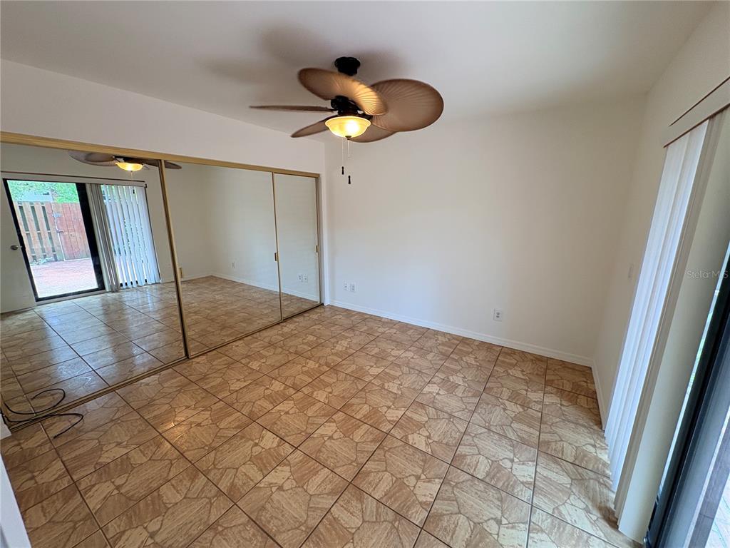 An empty room features tiled flooring, a ceiling fan, and large mirrored closet doors — 18 CEDAR DUNES DRIVE, NEW SMYRNA BEACH, FL