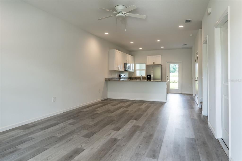 An open-concept kitchen and living area feature light gray wood-look flooring and white cabinetry — 5383 VISTA LAGO DRIVE, ORLANDO, FL