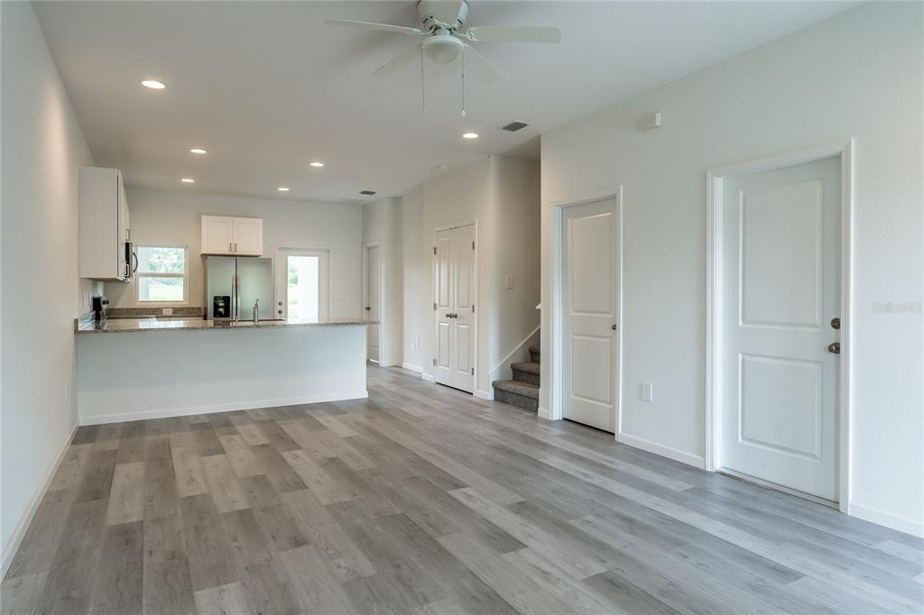 A bright, open-concept kitchen and living area with light gray wood-look flooring and white walls — 5383 VISTA LAGO DRIVE, ORLANDO, FL