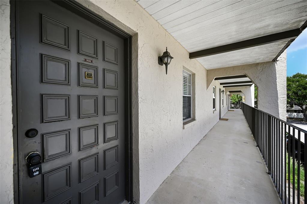 A dark gray door with a keypad lock sits on an outdoor apartment balcony — 8765 BARDMOOR BOULEVARD UNIT 306, SEMINOLE, FL