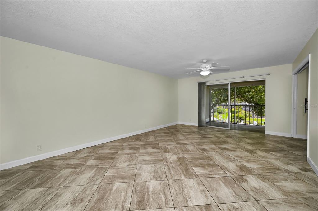 An empty living room with light-colored walls, tile flooring, and a sliding glass door — 8765 BARDMOOR BOULEVARD UNIT 306, SEMINOLE, FL