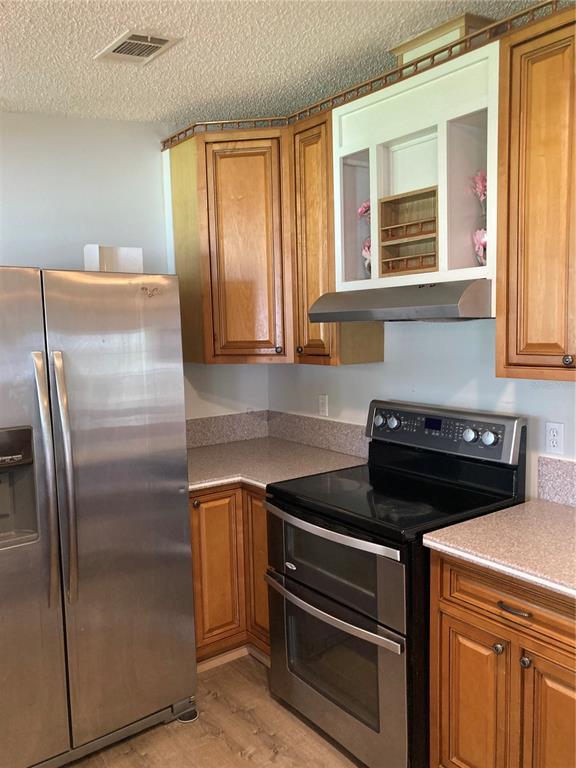 A kitchen features wood cabinets, stainless steel appliances, and speckled laminate countertops — 1038 20TH STREET, OKEECHOBEE, FL