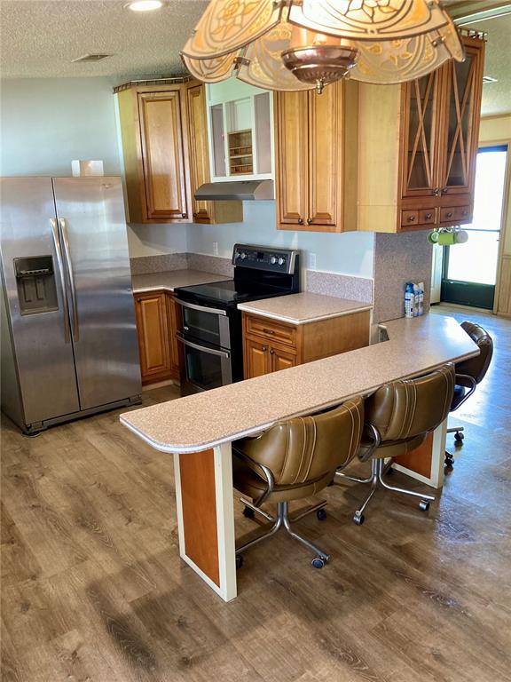 A kitchen features wood cabinets, stainless steel appliances, and a breakfast bar with rolling chairs — 1038 20TH STREET, OKEECHOBEE, FL