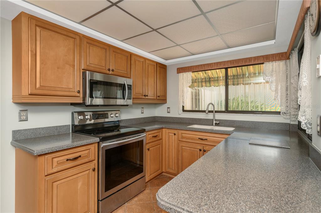 A kitchen with wood cabinets, stainless steel appliances, and gray countertops — 3825 GLEN OAKS MANOR DRIVE, SARASOTA, FL