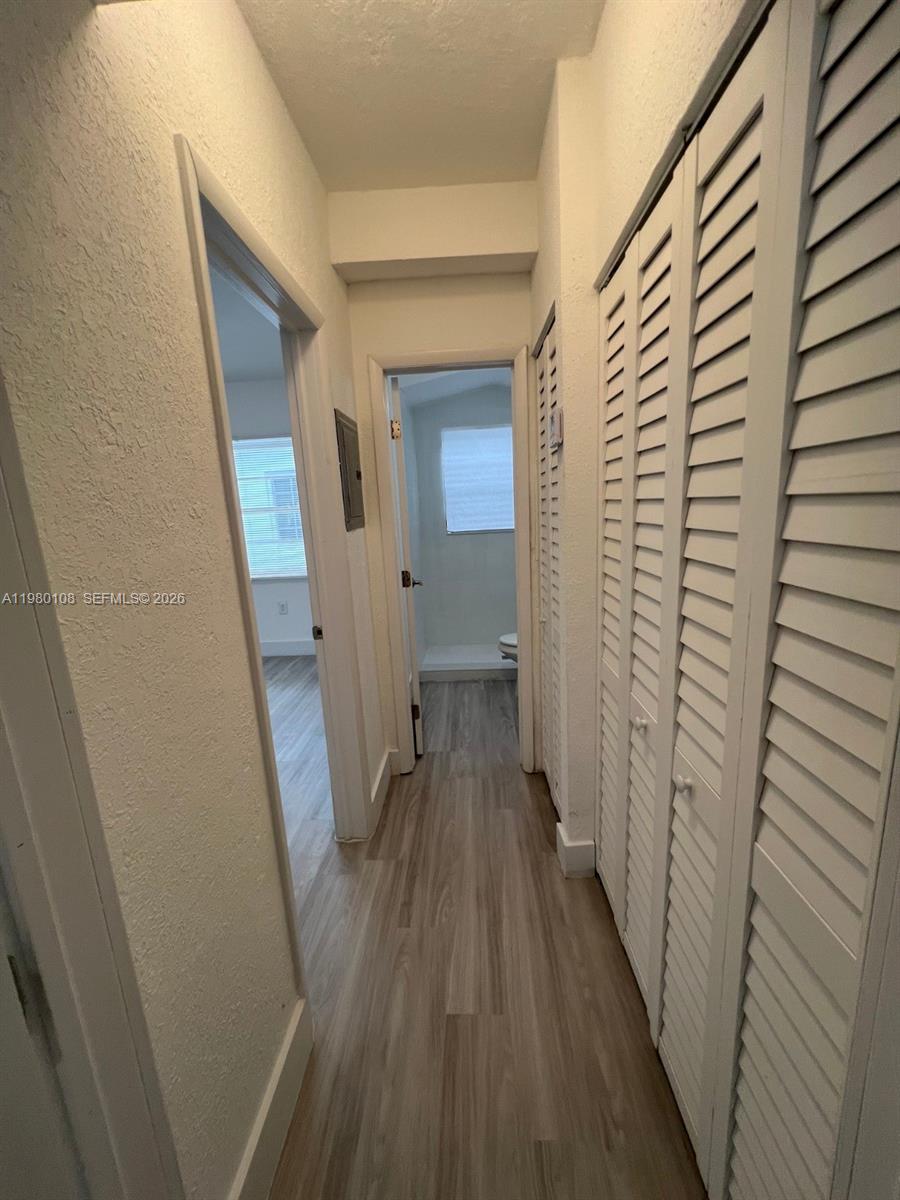 A hallway with light wood-look flooring leads to a bathroom and a bedroom — 1900 Calais Dr # 1904, Miami Beach FL 33141, MIAMI BEACH, FL