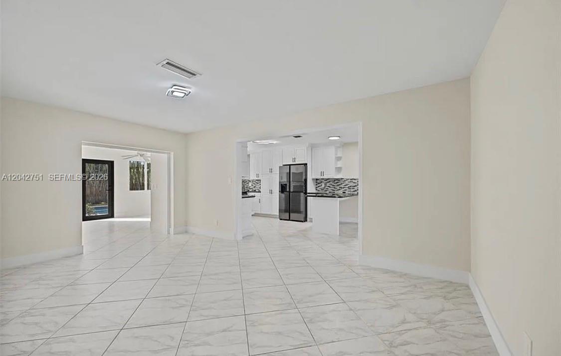 A bright, open-concept living area features white tile flooring and a view into the kitchen — 5300 Adams St, Hollywood FL 33021, HOLLYWOOD, FL