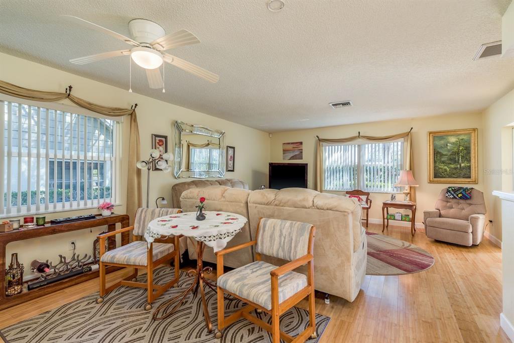 A living room with light walls, wood flooring, a ceiling fan, and two seating areas — 3413 ROCHELLE COURT, CLEARWATER, FL
